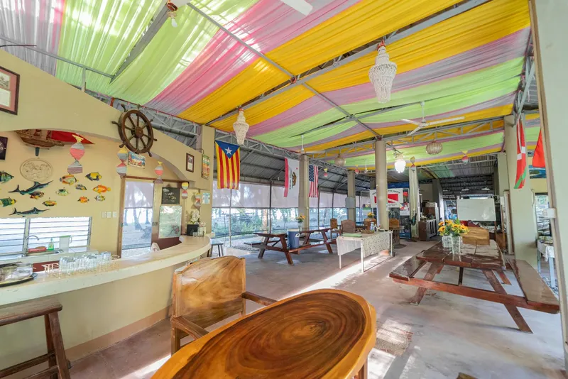 Espace détente intérieur avec bar, tables, décoration marine et drapeaux