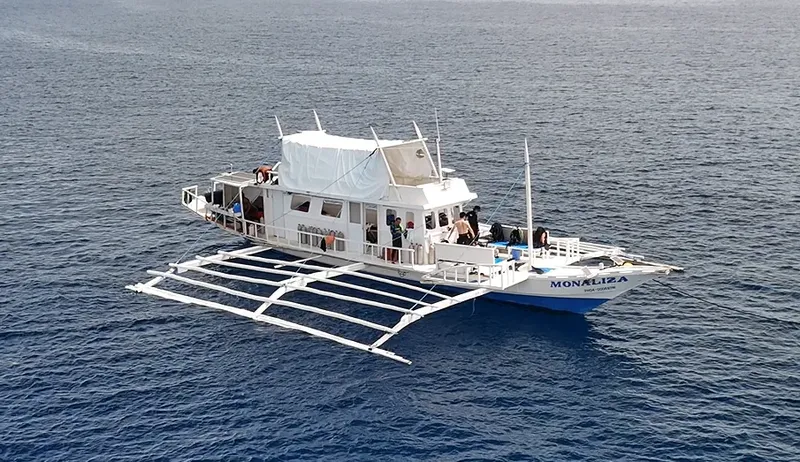 Bateau de plongée blanc avec des passagers et du matériel à bord