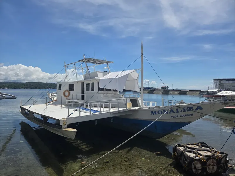 Bateau de plongée amarré à quai sous un ciel bleu nuageux