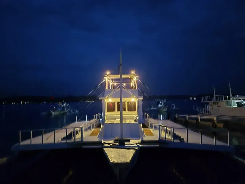 Bateau de plongée illuminé la nuit, amarré dans un port calme
