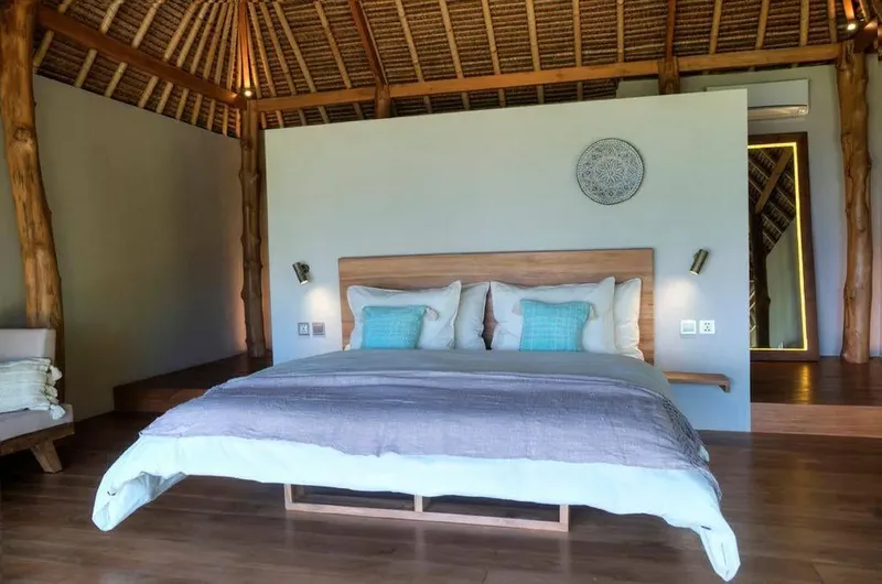Chambre avec grand lit, décoration sobre et éclairage mural chaleureux