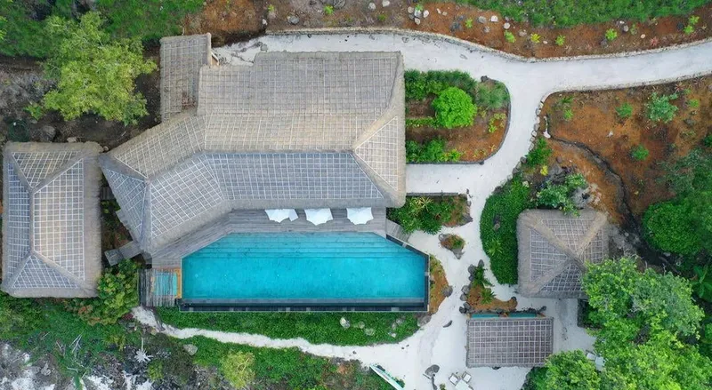 Vue aérienne d'un complexe avec piscine et bâtiments à toits de chaume