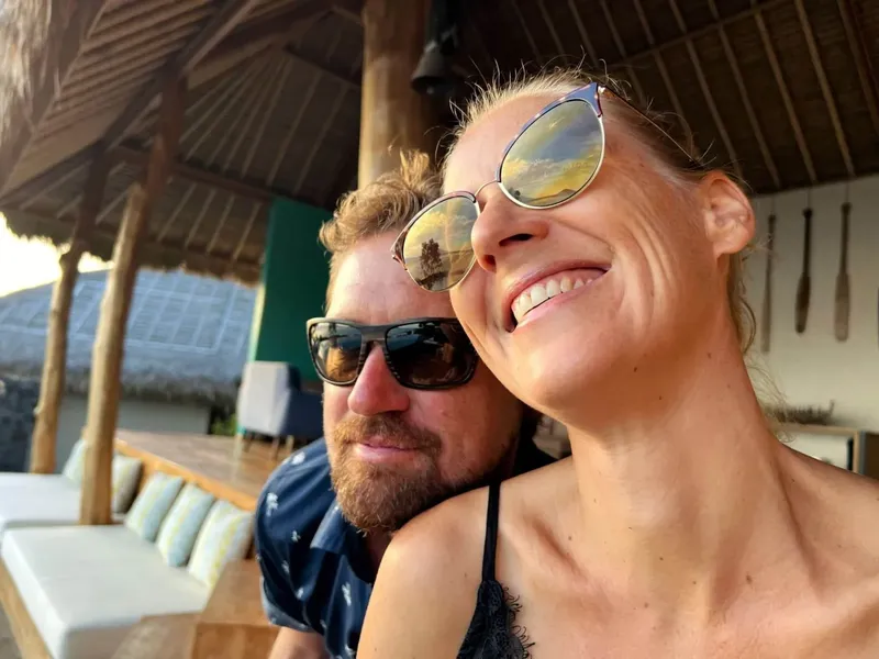 Deux personnes souriantes, portant des lunettes de soleil, regardent vers le haut
