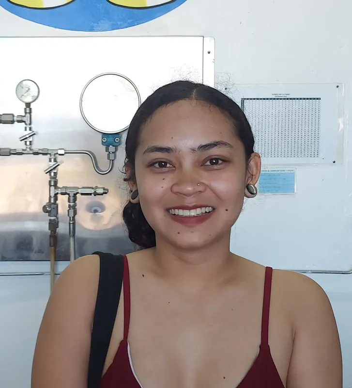 Portrait souriant d'une femme devant un mur avec des tuyaux
