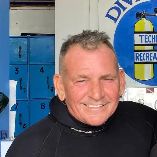 Portrait d'un homme souriant en combinaison de plongée devant des casiers