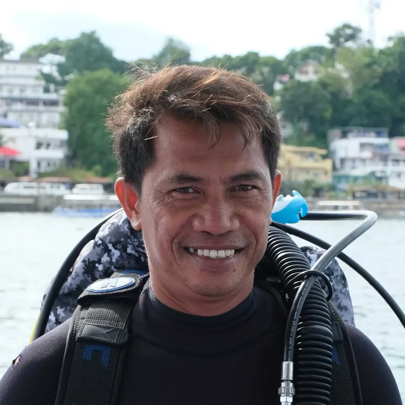 Portrait souriant d'un plongeur avec son équipement complet sur le dos
