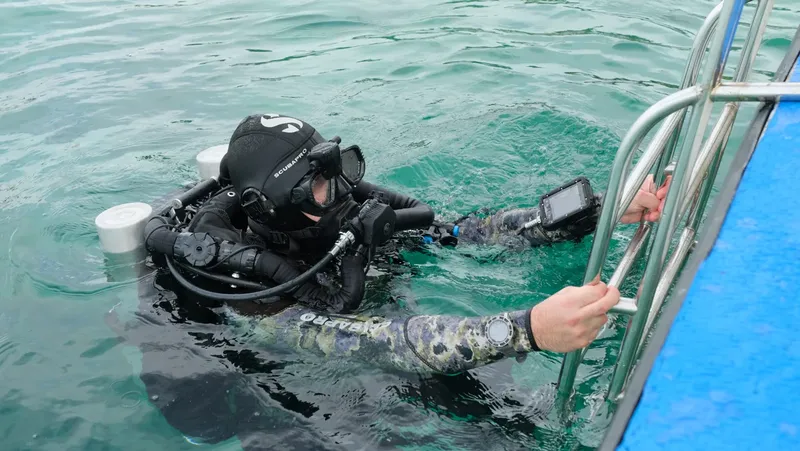 Plongeur équipé remonte à l'échelle d'un bateau en mer
