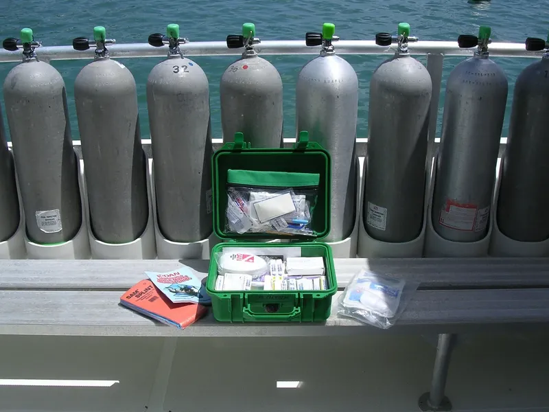 Bouteilles de plongée alignées sur un bateau avec une trousse de premiers secours