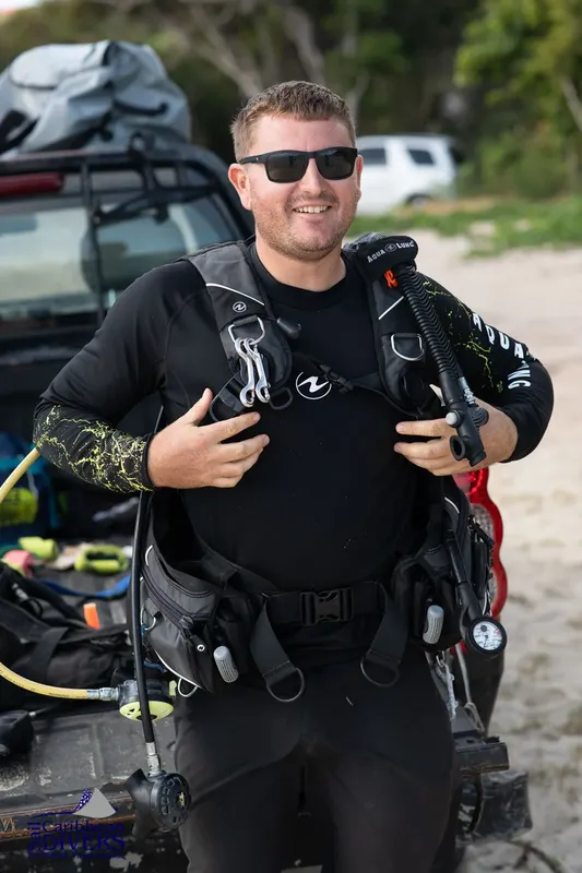 Plongeur souriant équipé de son matériel complet avant une immersion