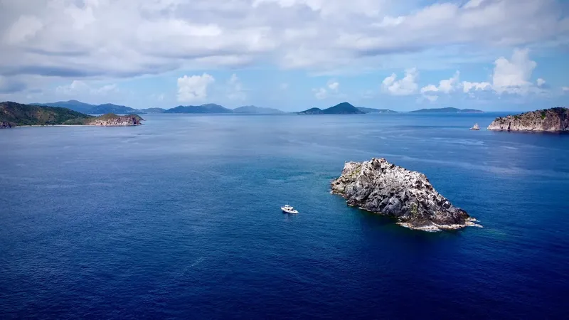 Vue aérienne d'un bateau en mer face à une île rocheuse