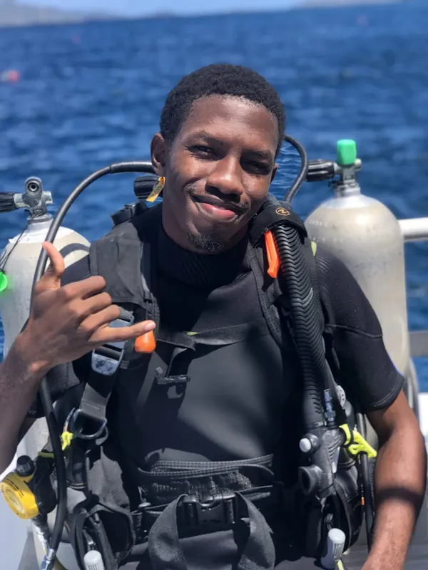 Plongeur souriant avec son équipement complet sur un bateau