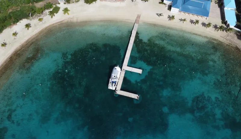 Vue aérienne d'un bateau amarré à un ponton dans une baie turquoise