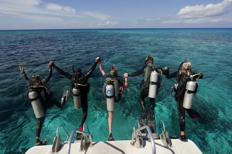 Plongeurs sur le point de sauter d'un bateau en mer turquoise