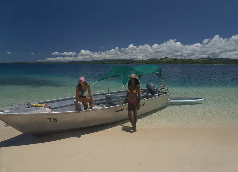 Deux femmes sur une plage avec un petit bateau à moteur