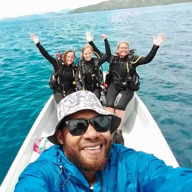 Quatre plongeuses et un homme sourient à bord d'un bateau