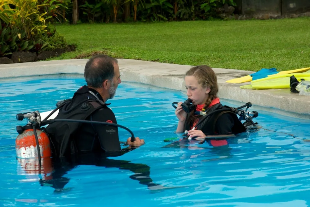 Instructeur et élève en combinaison de plongée dans une piscine