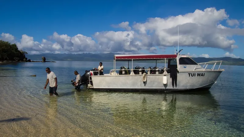Bateau de plongée échoué sur une plage de sable blanc avec des personnes