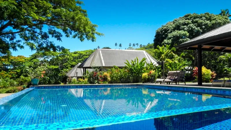 Piscine turquoise devant un bâtiment tropical luxuriant et végétation dense