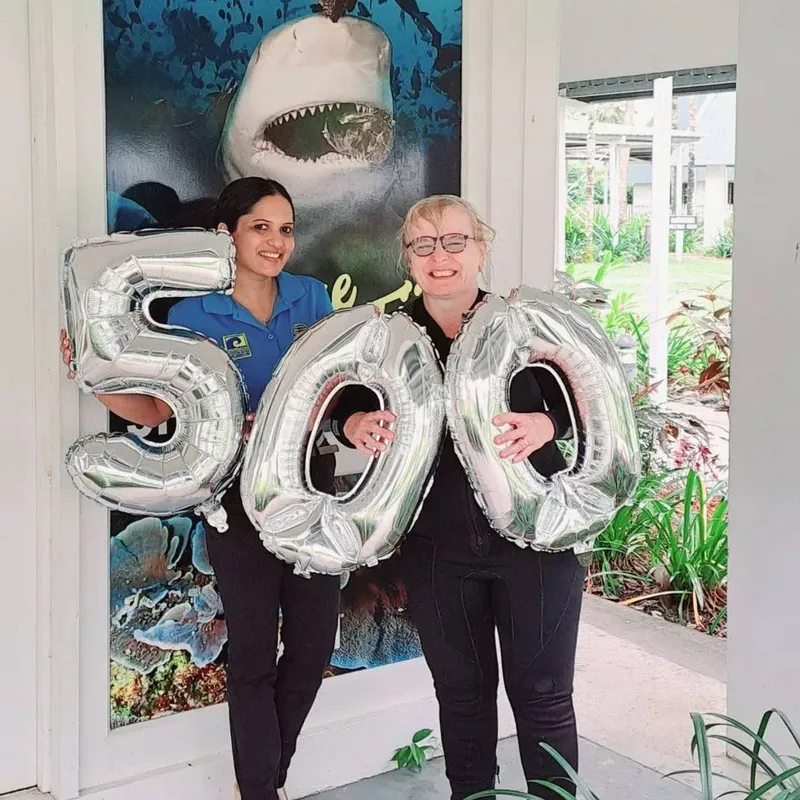 Deux femmes souriantes tenant des ballons argentés en forme de chiffres