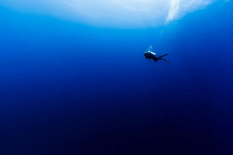 Plongeur solitaire évoluant dans une eau bleue profonde et lumineuse