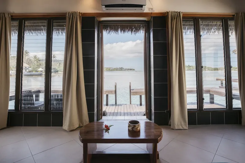 Vue sur l'océan depuis une pièce avec une table basse et rideaux