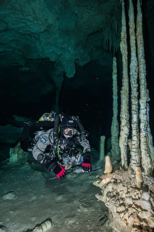 Deux plongeurs explorent une grotte sous-marine avec des stalactites