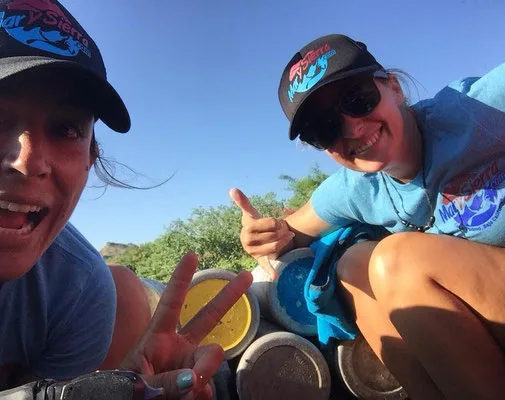 Deux femmes souriantes posent devant des bouteilles de plongée bleues