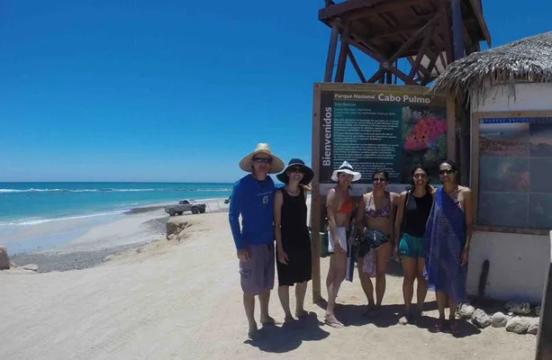 Groupe de personnes souriantes devant un panneau d'information touristique