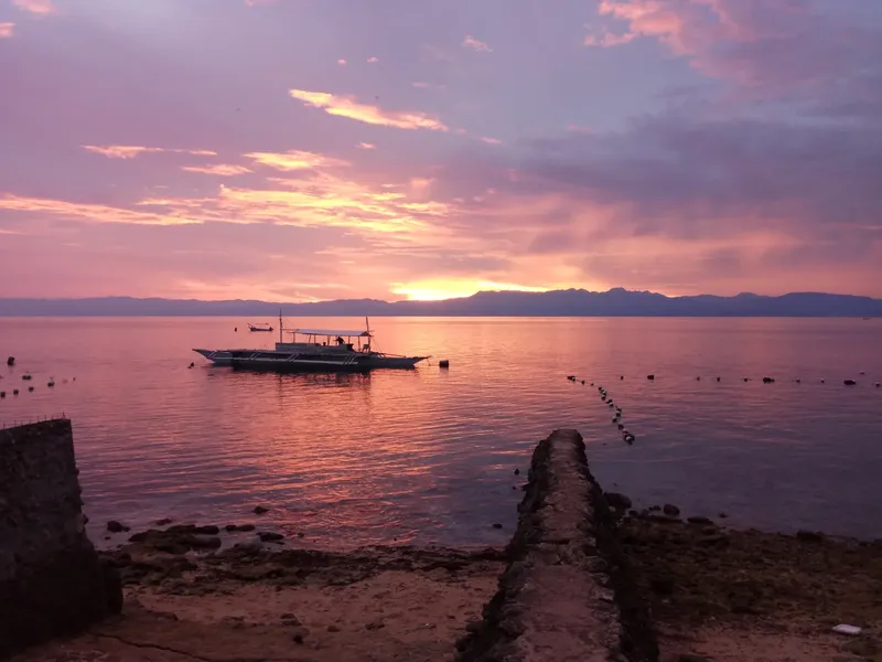 Coucher de soleil sur la mer avec un bateau de pêche amarré