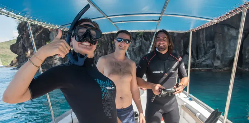 Trois personnes souriantes à bord d'un bateau de plongée en mer