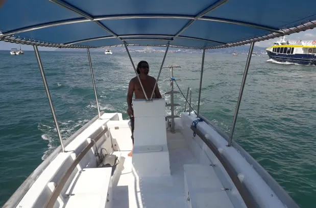 Homme à la barre d'un bateau de plongée en mer calme
