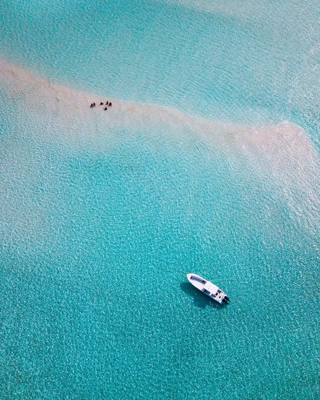 Vue aérienne d'un bateau et de personnes dans une eau turquoise claire