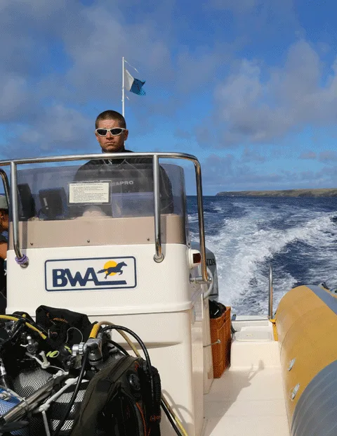 Plongeur sur un bateau semi-rigide en mer, portant des lunettes de soleil