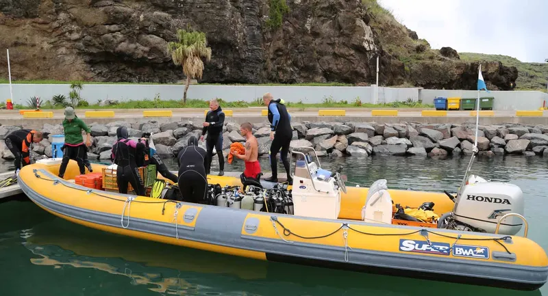 Plongée : des personnes équipent un bateau pneumatique jaune au port