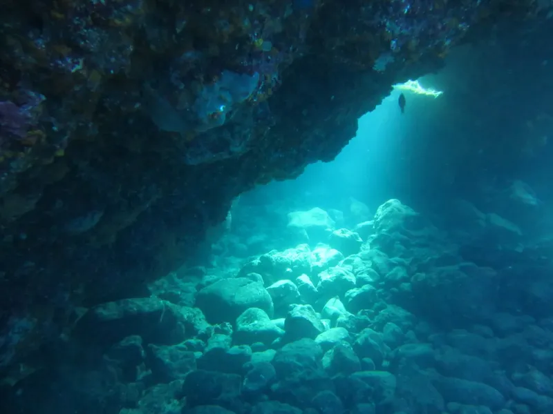 Vue sous-marine d'une roche avec un plongeur éclairé par le soleil