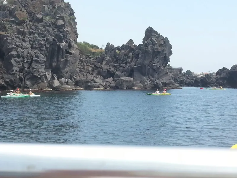 Personnes en kayak naviguent près de falaises rocheuses sous un ciel clair