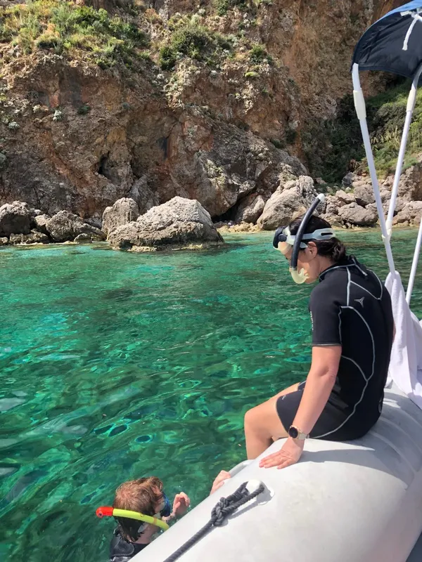 Deux personnes en combinaison regardent l'eau turquoise depuis un bateau