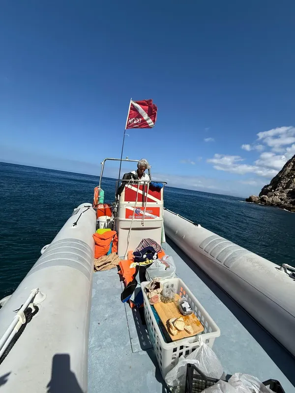 Personne à bord d'un semi-rigide avec du matériel de plongée visible