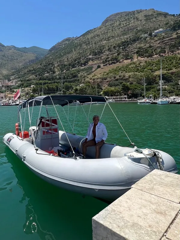 Homme assis dans un bateau pneumatique avec des bouteilles de plongée