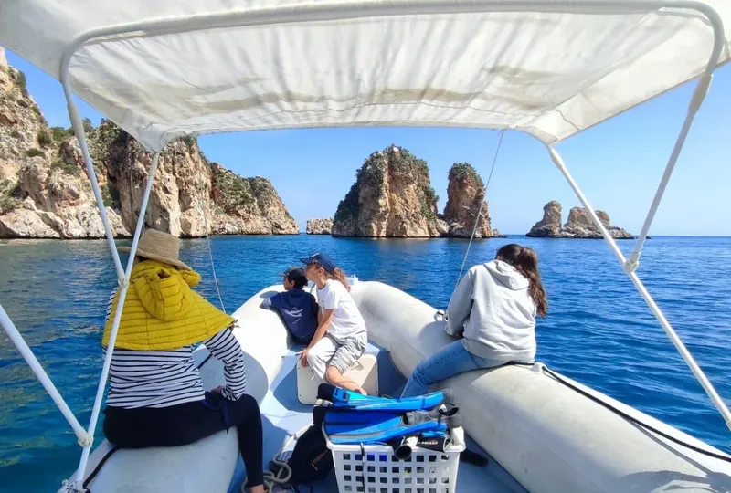 Personnes à bord d'un bateau pneumatique en direction de rochers côtiers