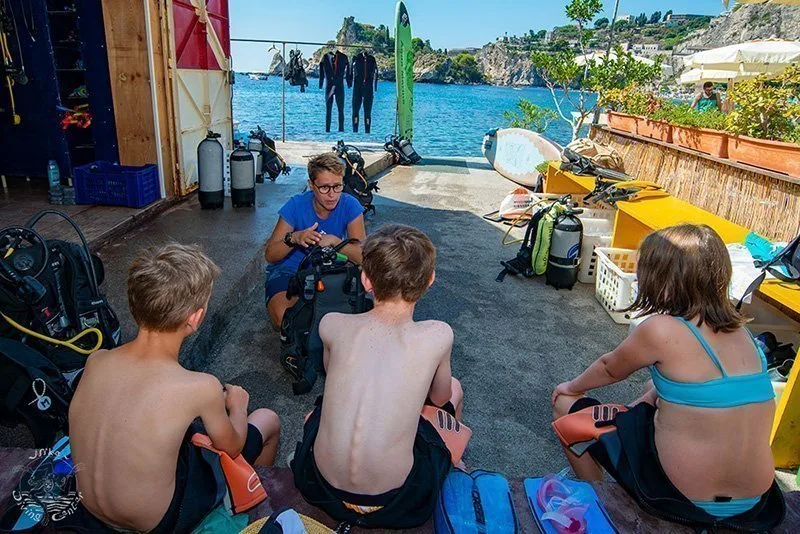 Instructeur expliquant l'équipement de plongée à des enfants attentifs