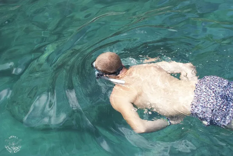 Homme nageant en surface avec masque et tuba dans une eau turquoise