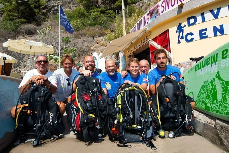 Groupe de plongeurs souriants avec leur équipement devant le centre