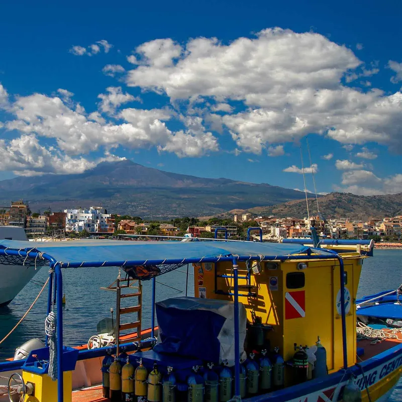 Bateau de plongée amarré avec des bouteilles et un paysage côtier