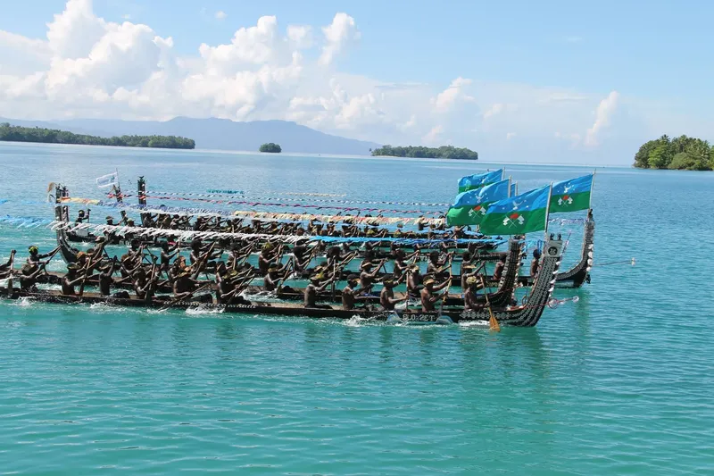 Une foule rame sur un long bateau traditionnel en mer turquoise