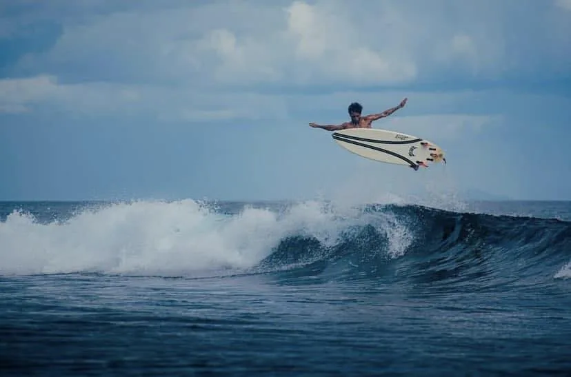 Surfeur effectuant une figure aérienne au-dessus d'une vague déferlante