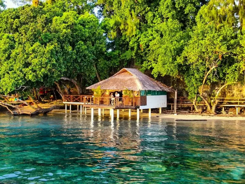 Petite cabane sur pilotis au bord d'une eau turquoise et claire