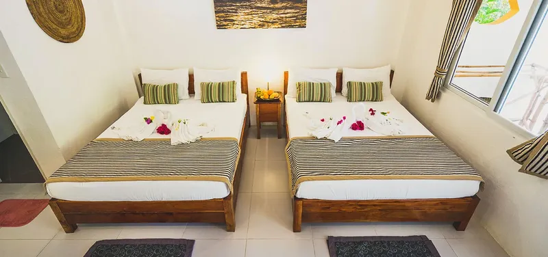 Chambre avec deux lits simples décorés de fleurs et serviettes