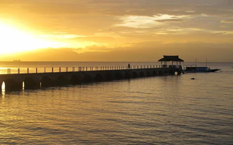Ponton en bois menant à un bateau au coucher du soleil