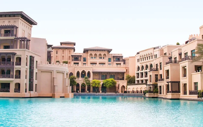 Architecture beige avec arcades, reflet dans l'eau turquoise calme